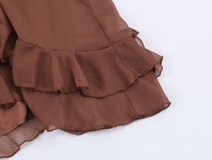 Detailed view of brown chiffon dress layers with delicate ruffles and sheer fabric texture