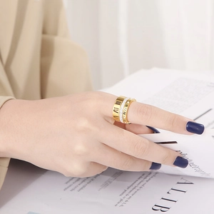 Close-up of stacked gold Roman numeral ring and sparkling diamond band on model's hand