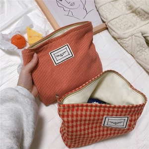 Detail of orange houndstooth cotton makeup bag with metal zipper and woven label