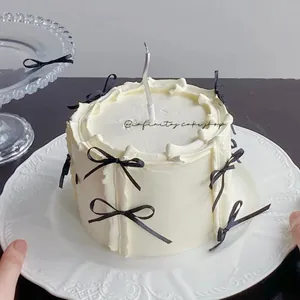 Detail of ballet style cake with black silk bows and silver candle on ceramic plate