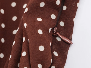 Dettaglio di abito marrone a pois con cerniera invisibile su tessuto in chiffon leggero