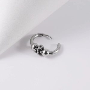 Macro shot of punk style stainless steel hoop earring with vintage beads and charms