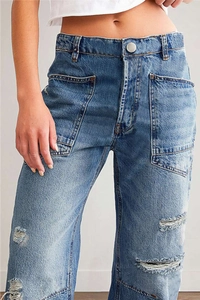 Detail van blauwe gescheurde jeans met wijde pijpen, grote vierkante zakken en denim textuur