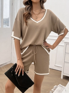 Detail of V-neck knit top and drawstring shorts with white trim in beige color