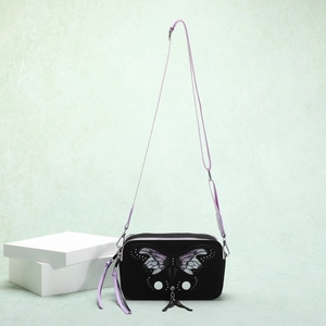 Detail of black crossbody bag with purple butterfly wings, silver studs, and leather tassel
