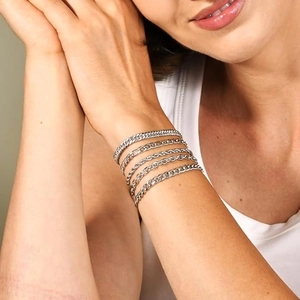 Close-up detail of silver Cuban and Figaro chain bracelet set worn on a male wrist