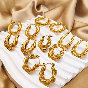 Detailed view of various gold-plated stainless steel twisted hoop earrings on silk