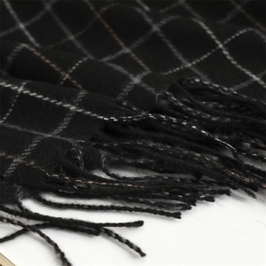 Macro detail of soft black and white plaid scarf featuring classic fringe tassels at the edge