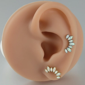 Detail showing G23 titanium opal ear studs on a silicone ear model with marquise cut stones