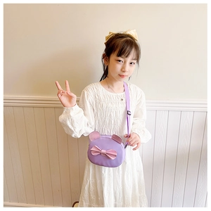 Detail of a purple glittery cat-shaped crossbody bag with bow worn by a child