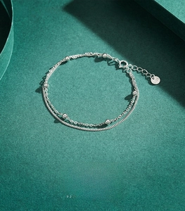 Macro detail of S925 sterling silver double-layered bracelet with beads and lobster clasp