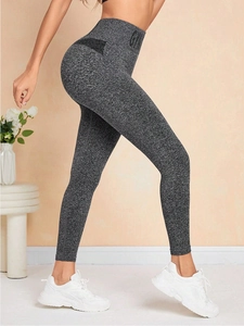 Détail du legging de sport gris taille haute montrant l'effet galbant et l'imprimé GYM