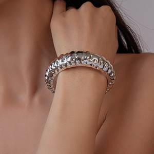 Macro view of silver chunky open bangle featuring unique irregular lava texture