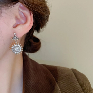Detail view of silver sun-shaped stud earrings with micro zircons on a model's ear