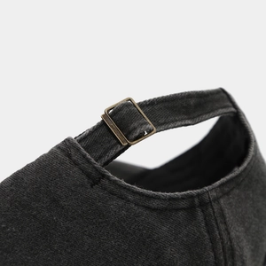 Detail of washed black denim baseball cap with vintage bronze metal buckle adjustment