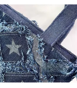 Close-up of denim tote bag featuring white star patterns and frayed fringe edges