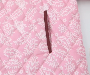 Detail of pink floral quilted fabric with deep red pocket trim and stitching patterns