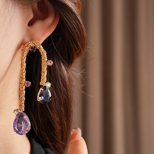 Detail of vintage gold twisted earrings with colorful gems and teardrop stones on model