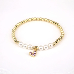 Detail of beaded bracelet with gold beads, white pearls, and purple zircon heart charm