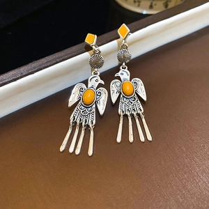 Close-up of vintage silver thunderbird earrings with bright yellow stone accents