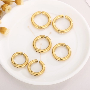 Vue détaillée de six boucles d'oreilles clips créoles dorées en acier sur plateau blanc