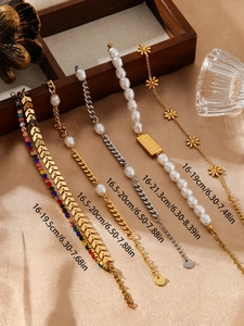 Detail of five assorted stainless steel bracelets featuring pearls and floral charms