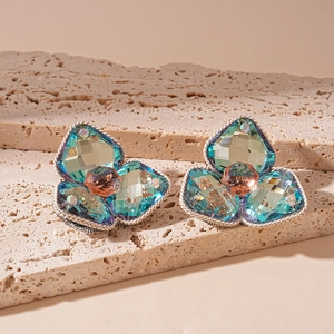 Macro shot of silver flower earrings with teal AB crystals and champagne pink studs