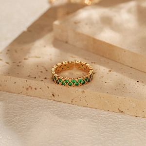 Detail of 18K gold plated heart ring with emerald green zircon stones on stone background