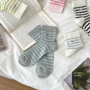 Flat lay of colorful striped crew socks with small letter embroidery on a white fabric