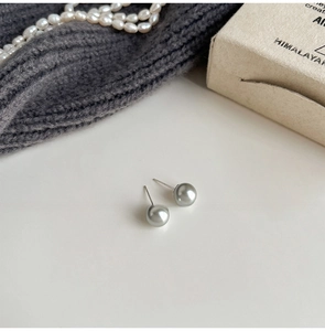 Detailed view of silver grey pearl studs featuring elegant round luster on silver needles