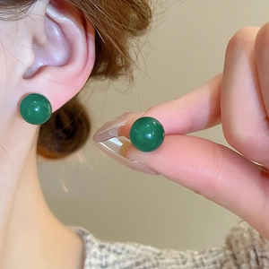 Close-up of model wearing a deep green round glass bead earring with a glossy finish