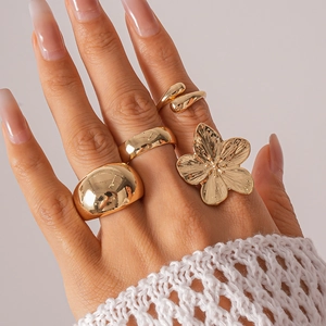 Detail of four gold geometric flower rings worn by model, showing polished metal texture