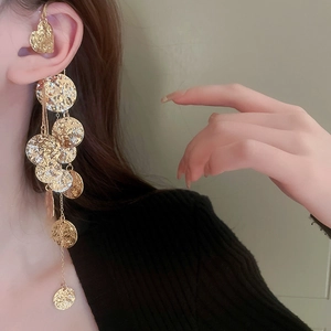 Dettaglio di un ear cuff dorato con paillettes stropicciate e lunghe nappe su modella