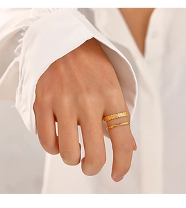 Détail d'une bague double couche dorée avec motif d'épi de blé sur la main d'une femme