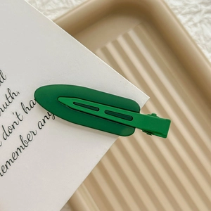Detail of matte green seamless hair clip showing layered design and smooth texture