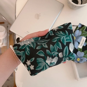 Close-up of green floral jacquard mini storage bag with zipper and textile texture