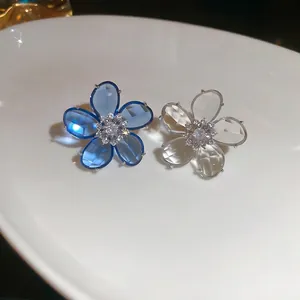 Elegant zircon crystal flower ear clips in blue and clear styles on a white plate