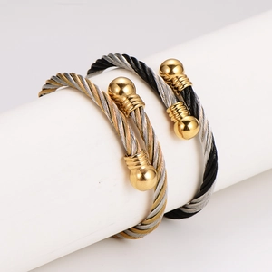 Retro stainless steel twisted cable bangles in gold and silver set on white pillar