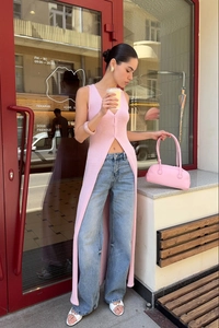Outdoor street view of pink long sleeveless knit cardigan and wide leg blue jeans