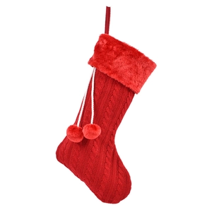 Chaussette de Noël en tricot rouge avec revers en peluche et pompons blancs sur fond blanc