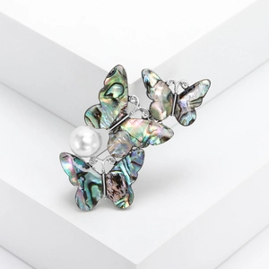 Vintage alloy butterfly brooch with abalone shell inlay and pearl on white decor