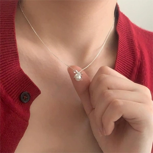 Elegant 925 silver necklace with pearl bow pendant worn on a model with red cardigan