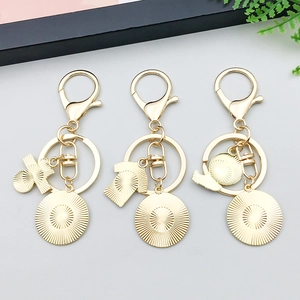 Dettaglio di portachiavi dorati con ciondoli a forma di T-shirt e chiusura a moschettone