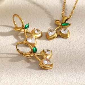 Detailed view of cherry pendant necklace and earrings set with green and clear crystals