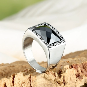 Vue macro d'une bague homme en acier avec une pierre noire rectangulaire et des gravures