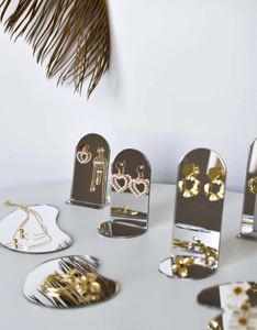 Macro view of arched vertical mirror and cloud-shaped tray for jewelry display photography