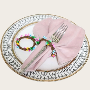 Handmade Easter napkin rings with colorful berry beads on a pink napkin and white plate