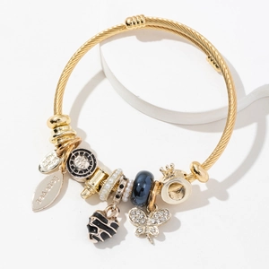 Golden charm bracelet with butterfly, pearl, and heart pendants on a round display
