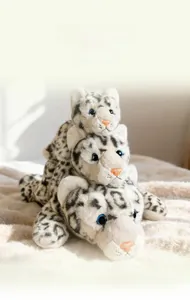 Three plush snow leopard toys in different sizes with realistic faux fur and blue eyes
