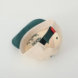Detail view of cotton kid's cap with embroidered letters and adjustable green strap